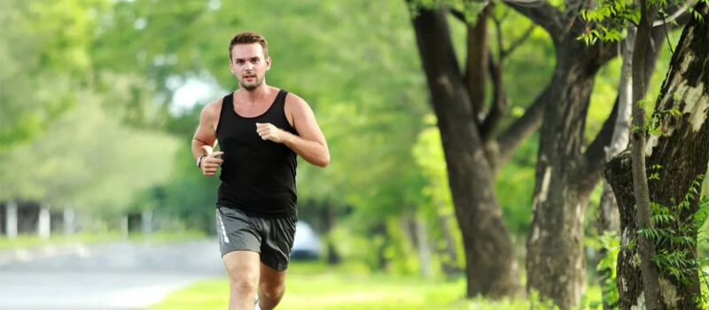 A man runs energetically in a park, embodying a healthy lifestyle with Ginglitz Plus as his fitness companion.