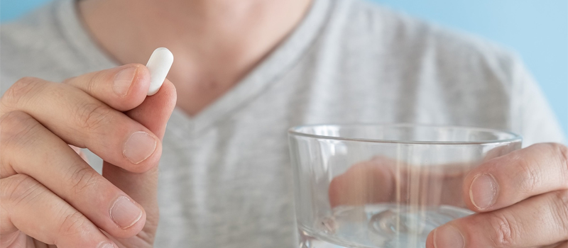 A man holds a Gluta White capsule in his hand, showcasing its ingredients and health benefits.