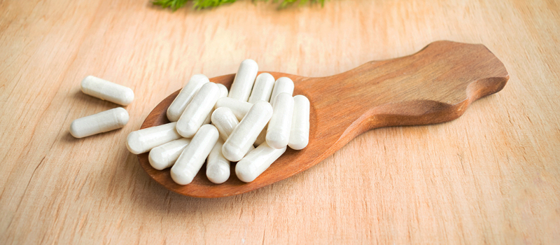 A wooden spoon holds white pills, representing Gluta White Capsules in contrast to various whitening products.