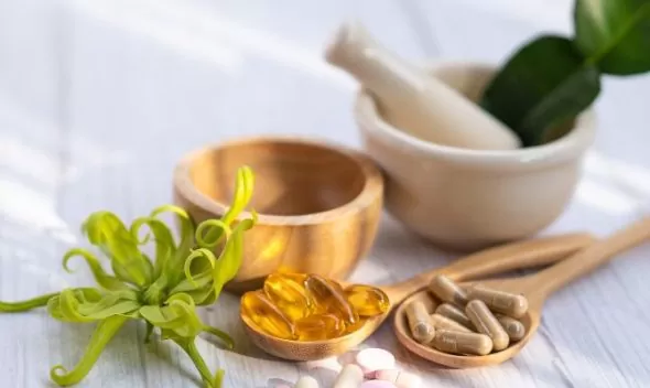 a wooden spoon with pills and a mortar and pestle