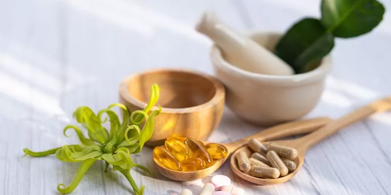 a wooden spoon with pills and a mortar and pestle