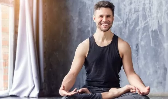 A man sits in a yoga pose, embodying tranquility and focus, while promoting overall wellness with Ginglitz Plus Capsules.