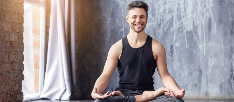 A man sits in a yoga pose, embodying tranquility and focus, while promoting overall wellness with Ginglitz Plus Capsules.