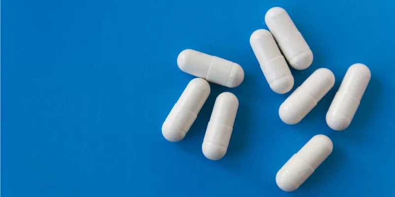 White Gluta White capsules arranged on a blue surface, promoting fast whitening benefits for skin enhancement.